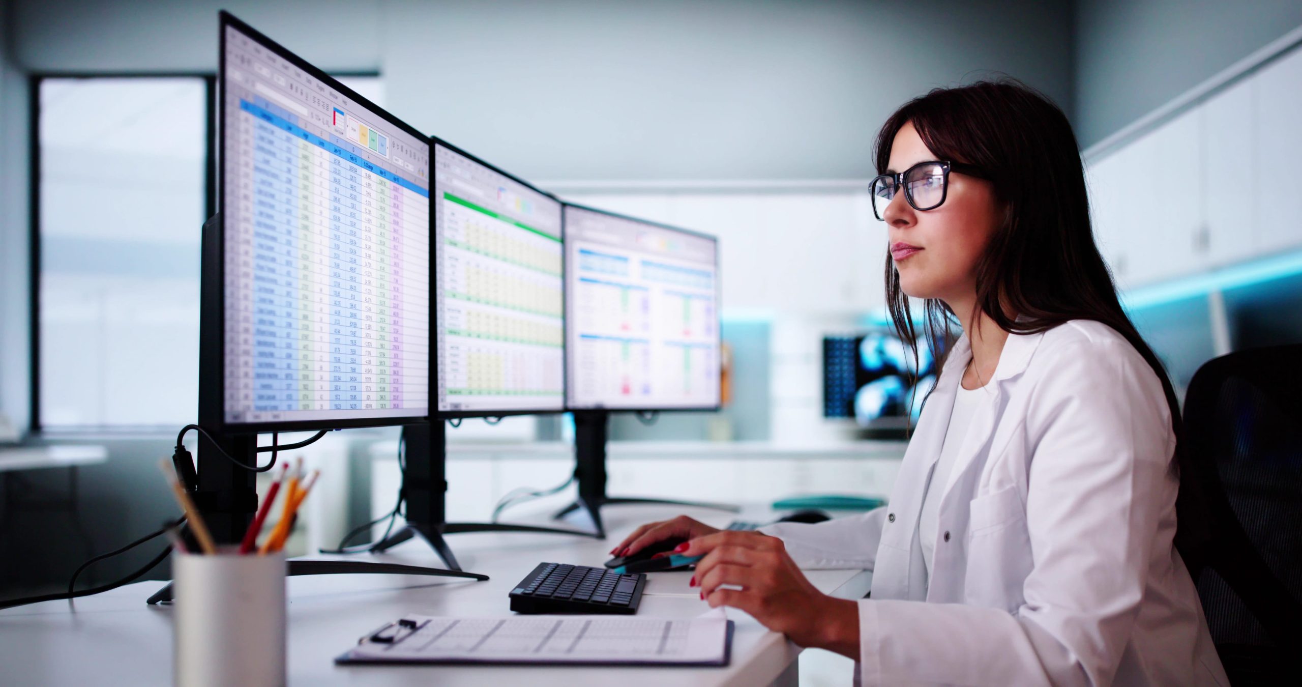 Clinician reviewing structured healthcare data on monitors